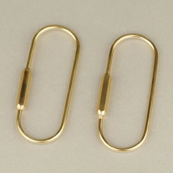 A pair of gold brass key ring carabiner clips or keychain bag charms.