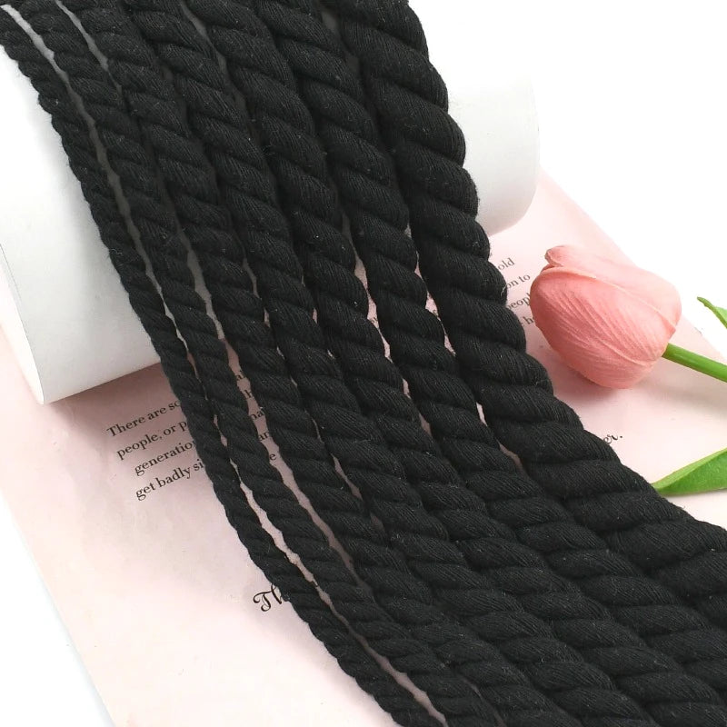 Fil de coton torsadé noir pour macramé et loisirs créatifs, présenté sur du papier rose.