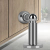 A silver magnetic door stopper installed on a wooden cabinet door.
