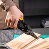 A hand is using heavy duty aviation tin snips shears to cut wood on a wooden board.