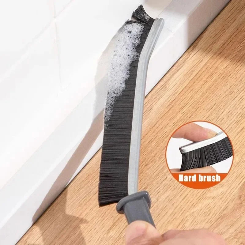 A black grout gap cleaning brush with a gray handle is shown against a white surface.