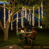 Dekorative LED-Lichterketten hängen von einem Baum und beleuchten einen Außenbereich zum Essen in der Nacht.
