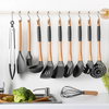 A set of stainless steel hanging kitchen utensils including spatulas and a whisk displayed on a white rack.