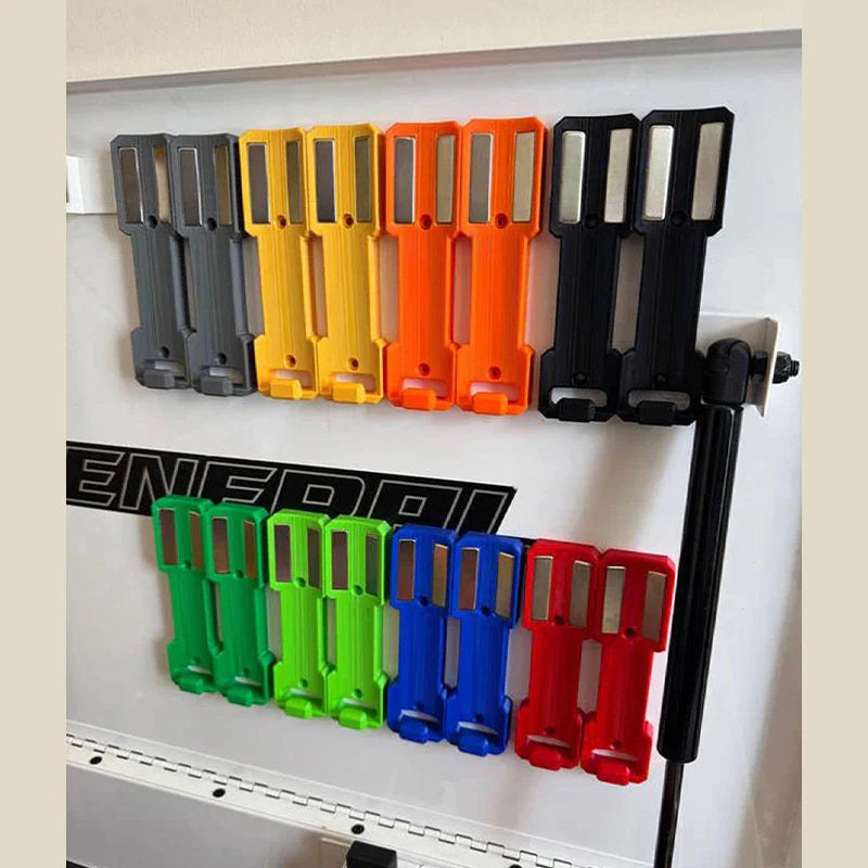 A row of magnetic spray can holders in various colors including gray, yellow, orange, and black mounted on a white panel.