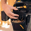 A hand is holding a black ToughBuilt tool belt with gold-colored tools attached, worn by a person.