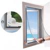 A hand is opening a window with a magnetic screen installed, showing a clear view of the outside.