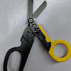 A pair of black and yellow tactical foldable shears with a measuring scale visible on the blade.