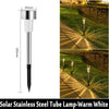 A vertical tube lamp with a silver finish used as an outdoor pathway light in a grassy landscape.