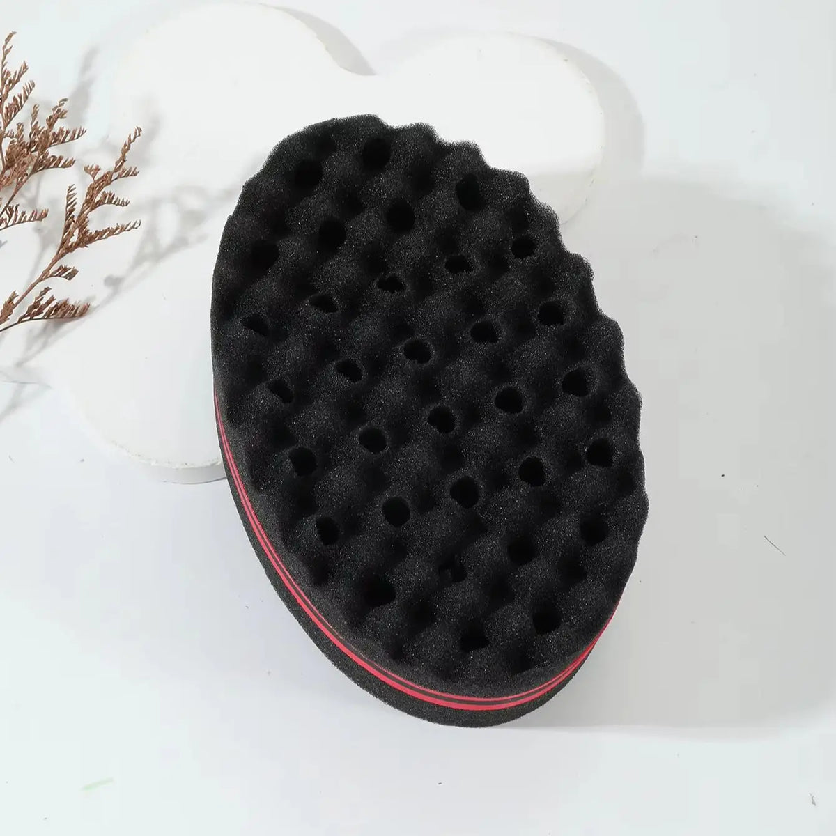 Brosse de coiffure en silicone noire bouclée avec une bordure rouge posée sur une surface blanche.
