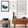 A display featuring a framed nature print, a line art drawing, and a wooden cabinet with decorative items.