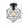 Black geometric wire frame chandelier lamp with an exposed clear light bulb.