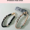A hand-braided leather phone lanyard with a silver clasp and a dark gray stone charm against a light background.