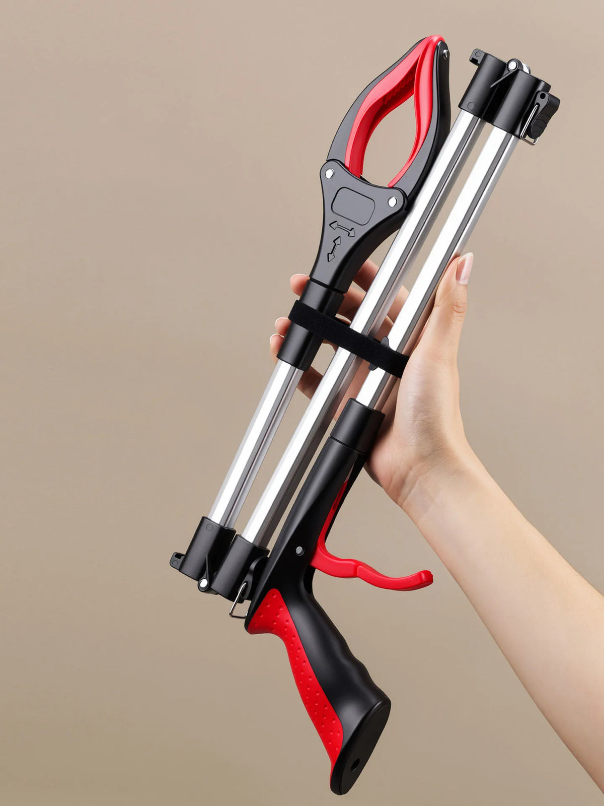 A hand holds a foldable litter picker and trash reacher tool with black, red, and silver components.