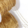 Close-up of gold stainless steel beading chains draped over a golden fabric background.