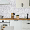 A kitchen cabinet and countertop featuring white shaker cabinets and a marble backsplash with pink veining.