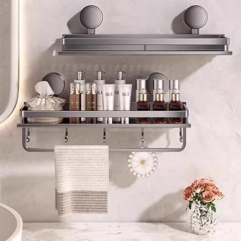 A metal wall mount shower caddy organizer displaying various skincare bottles and a folded towel on a bathroom shelf.