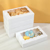 White decorative gift boxes filled with baked goods like cookies and pastries.