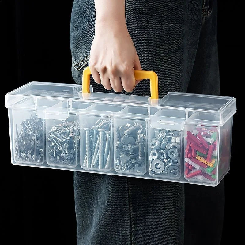A hand holds a clear plastic multi-compartment tool organizer box with yellow handles.