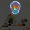 A glowing neon sign shaped like a skull with vibrant colors hangs on a wall above a table display.