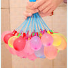 A hand is squeezing a bulk set of colorful water balloons, including pink, yellow, and blue ones.