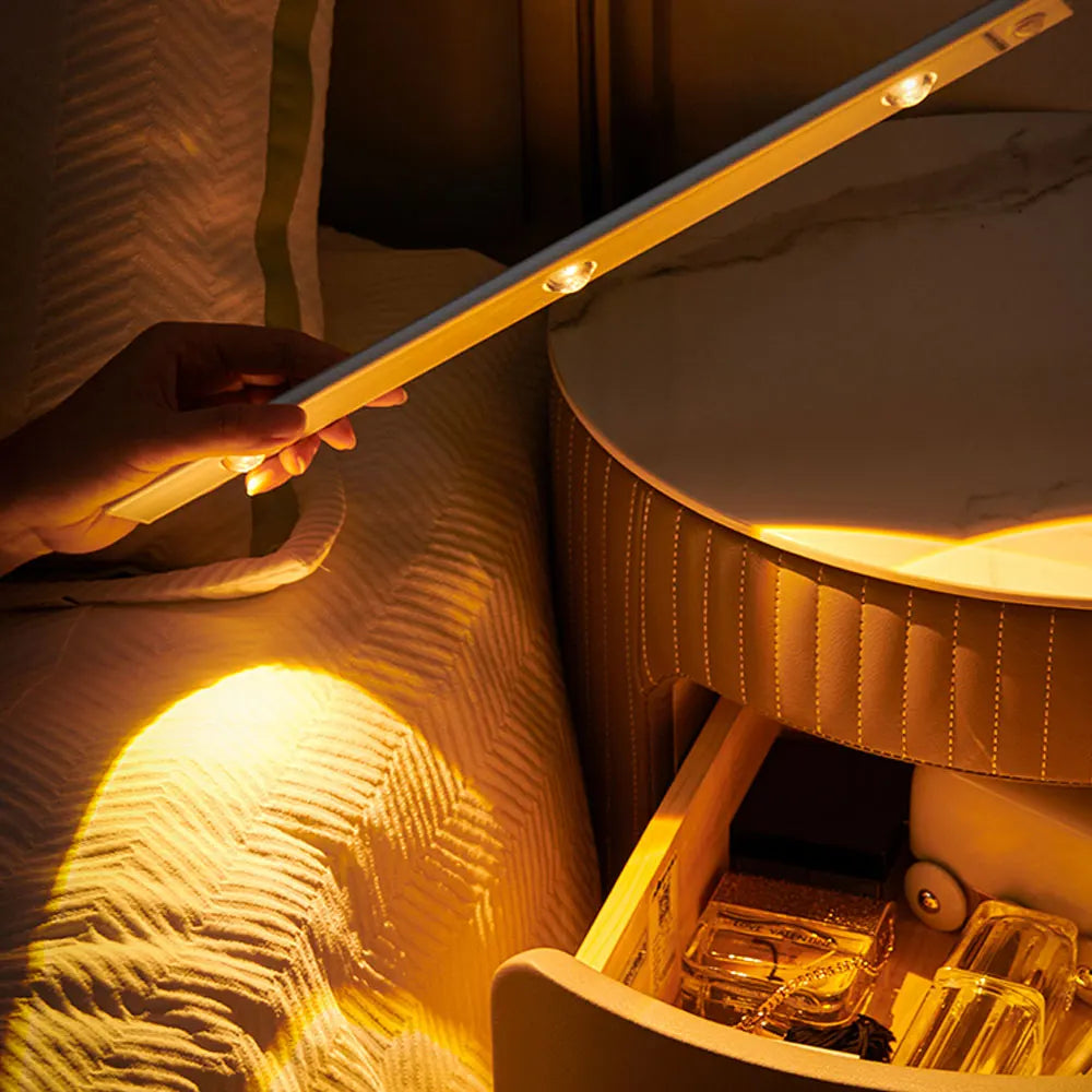 A hand illuminates a textured fabric with a bright yellow LED light from a long bar, highlighting the texture.