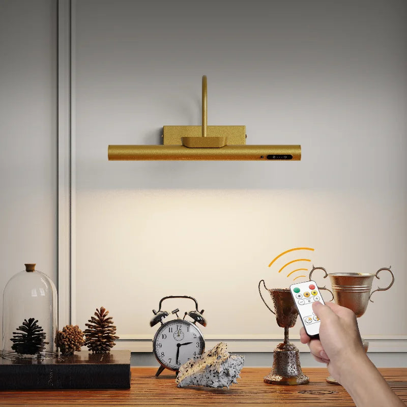 A wall mounted LED picture light with a wooden bar and remote control is displayed on a wooden surface.