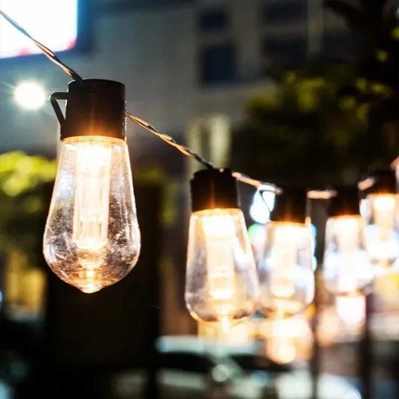 Lichterketten mit warm leuchtenden Glühbirnen, die nachts im Freien hängen
