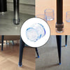 Close-up view of furniture leg foot protectors, showing clear silicone caps on dark metal legs and glass cups.