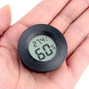 A hand holds a black digital indoor humidity and temperature meter displaying 27.4°C and 60%.
