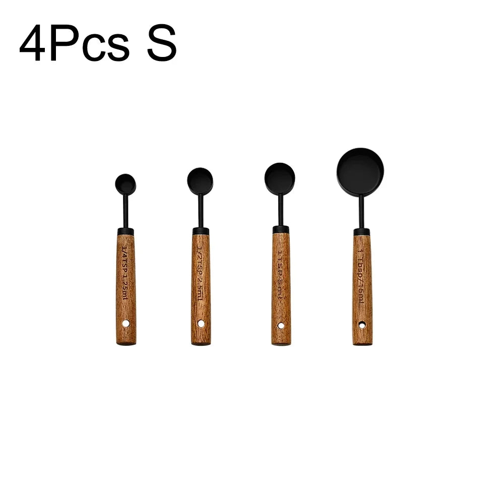 A set of four measuring spoons with black heads and wooden handles.