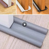 Close-up view of a metal door draft excluder seal strip installed on a wooden door frame.