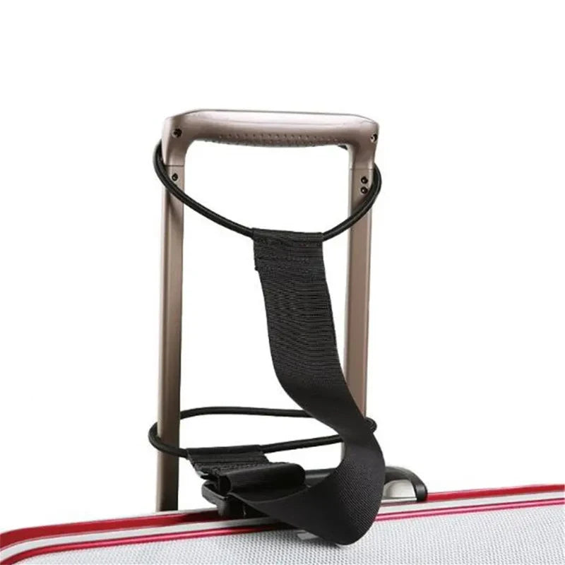 A black adjustable luggage strap carrier belt is shown resting on a red and white striped surface.