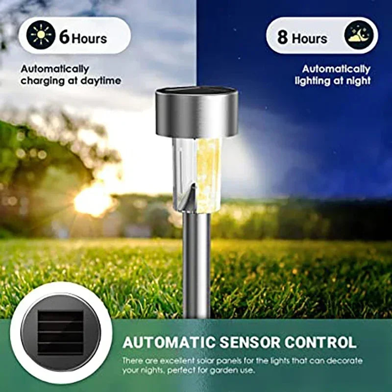 A silver solar powered outdoor garden lantern with a light, set against a green lawn and a dark background.