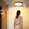 A woman stands near a modern staircase, looking at a rechargeable and magnetic motion sensor ceiling light.