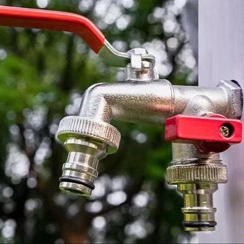 Primer plano de un grifo de jardín de latón plateado con manija roja y manguera flexible, contra un fondo verde desenfocado