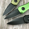 Un couteau de survie pliable compact avec une poignée verte et une lame noire posé sur une surface en bois.