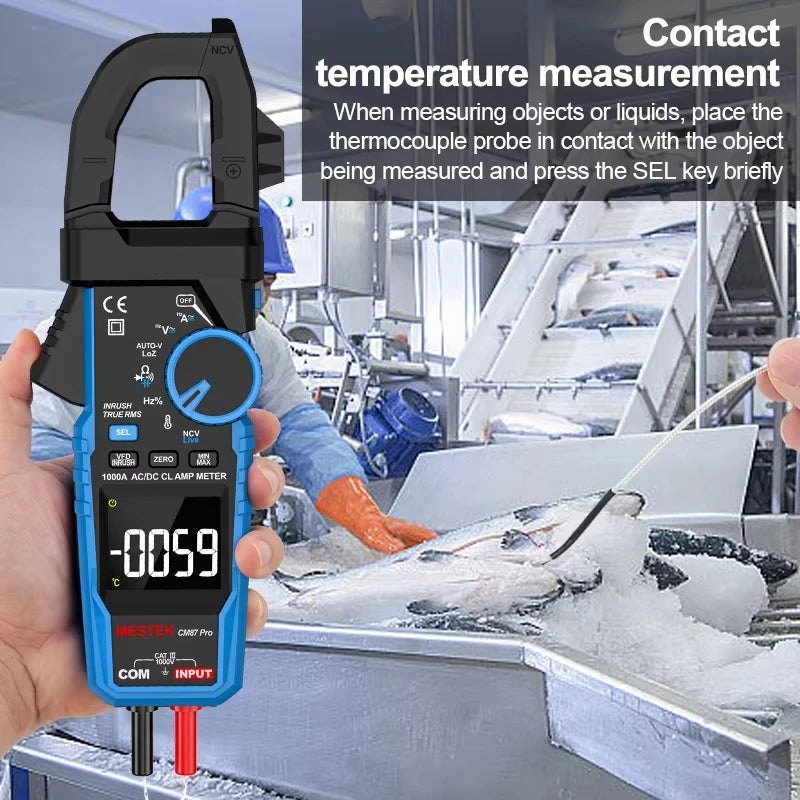 A hand holds a blue and black clamp meter for temperature measurement in an industrial setting.