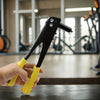 A hand holds a black heavy duty pop rivet gun kit with yellow handles on a dark surface.
