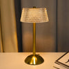 A brass table lamp with a textured glass shade sits on a white surface.