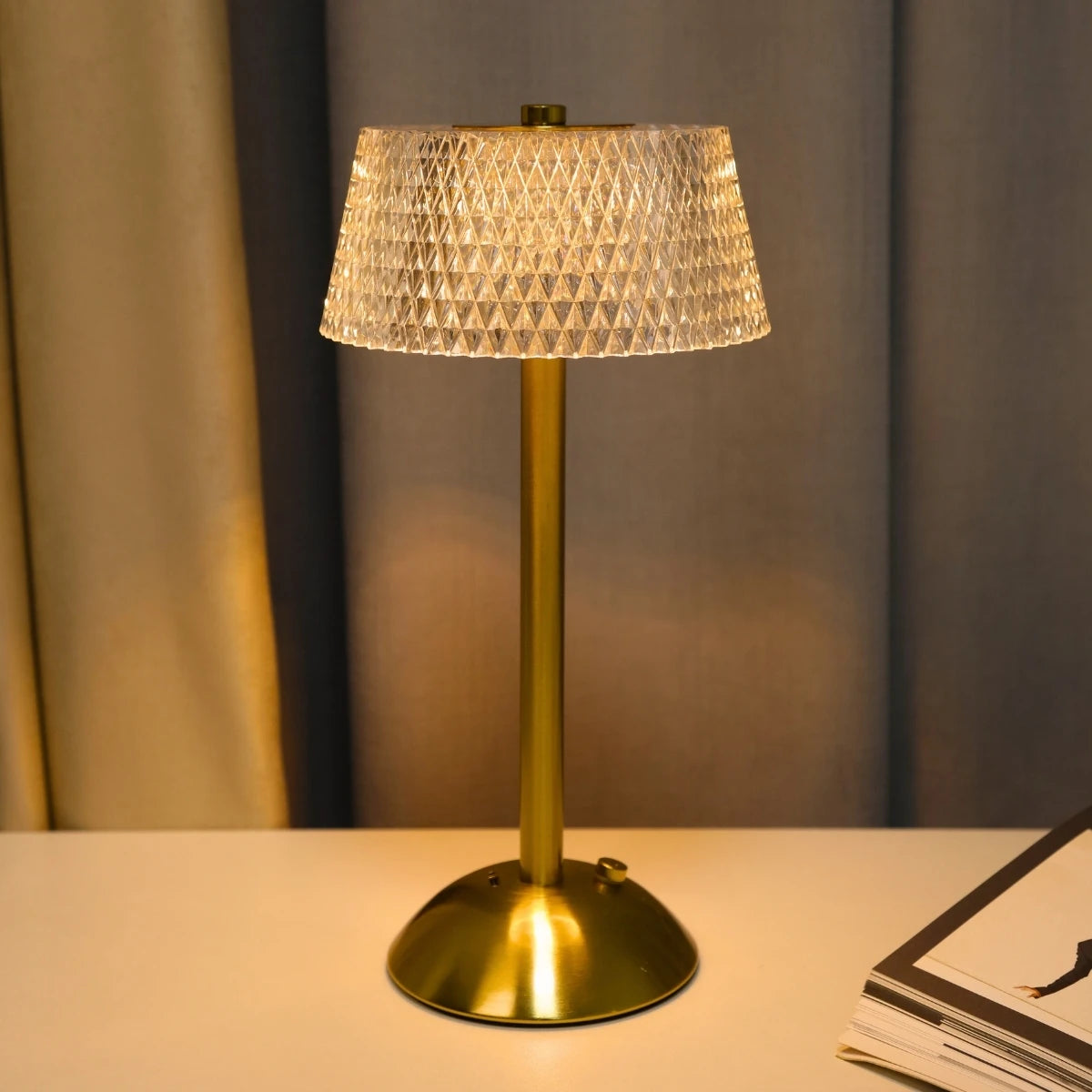 A brass table lamp with a textured glass shade sits on a white surface.
