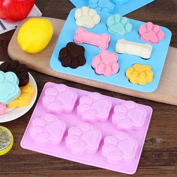 Un ensemble de moules en silicone roses et bleus en forme d'empreintes de pattes de chien, de différentes tailles et couleurs