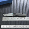 A folding knife with a carbon fiber handle and blade resting on a ruler.