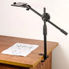 A black versatile overhead tripod with a boom arm and ring light positioned over a wooden table.