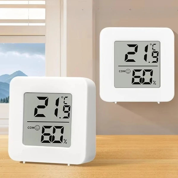 A white compact digital temperature and humidity gauge is shown on a wooden surface.