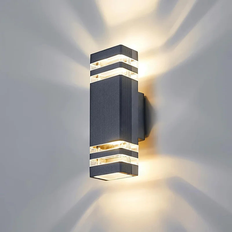 Moderne, rechteckige Wandleuchte mit gestufter LED-Beleuchtung wirft einen hellen Strahl auf eine graue Wand.