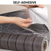 Hands are applying a silver self-adhesive wood grain wall panel to a dark gray roll.