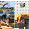 A hand holds a screwdriver bit holder with multiple hex shank bits and carabiners against a white pegboard.