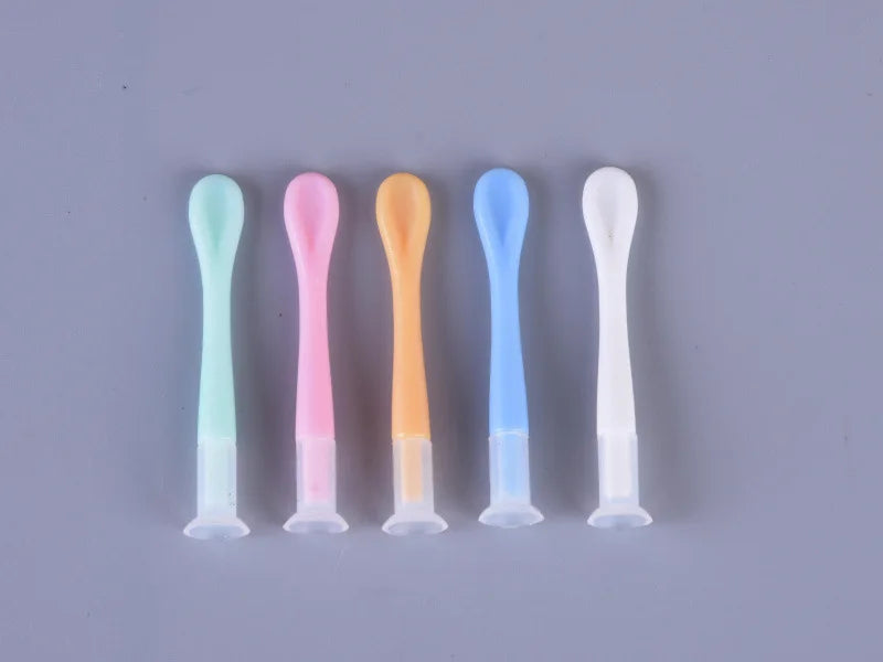 A set of five colored portable contact lens tools arranged in a row on a gray surface.