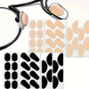A collection of self-adhesive anti-slip nose pads for eyeglasses in various shades of nude and black.