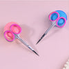 A pair of professional stainless steel nail cuticle trimmers with pink and blue handles are shown on a light pink background.